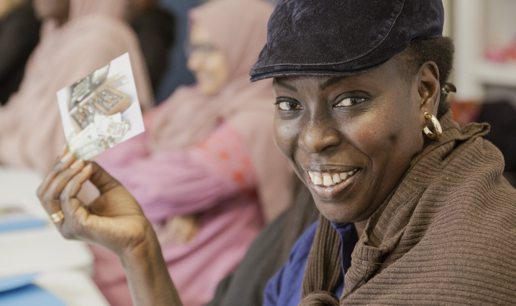 Une apprenante de l'Institut Enteam sourit en montrant une carte lors d'un atelier